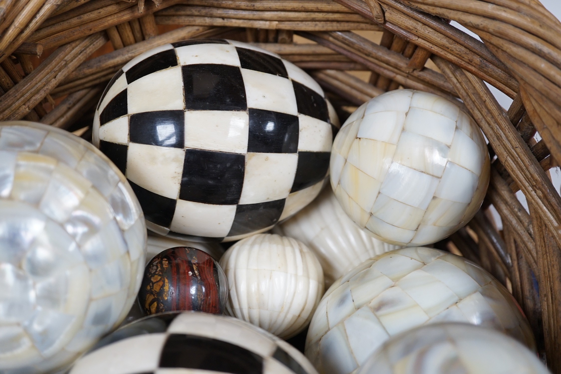 A basket of mother of pearl or bone veneered balls and other decorative balls